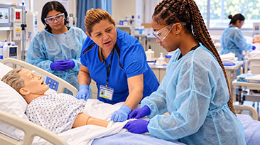 SOCHI instructor guides students practicing bedside care with a mannequin in a CNA skills classroom.